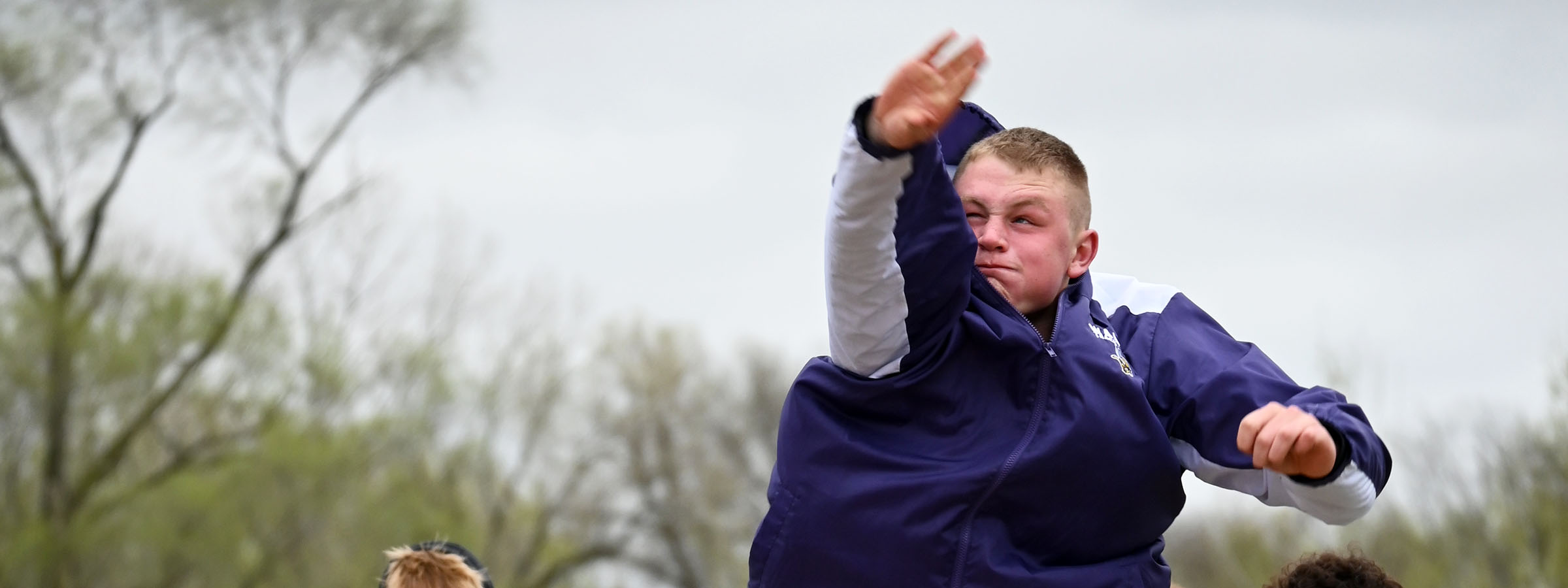 A young man in a purple shirt joyfully throws a frisbee in an outdoor setting, showcasing an active and playful moment.