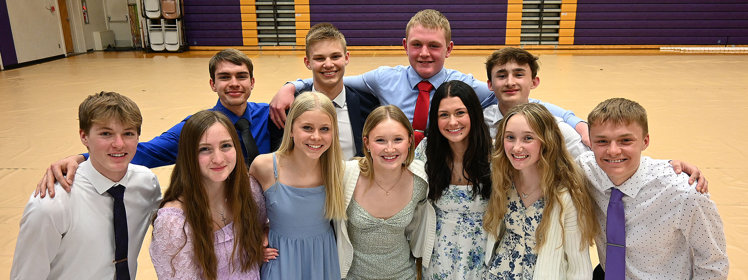 A group of young individuals smiling and posing together for a photo inside a gym setting.