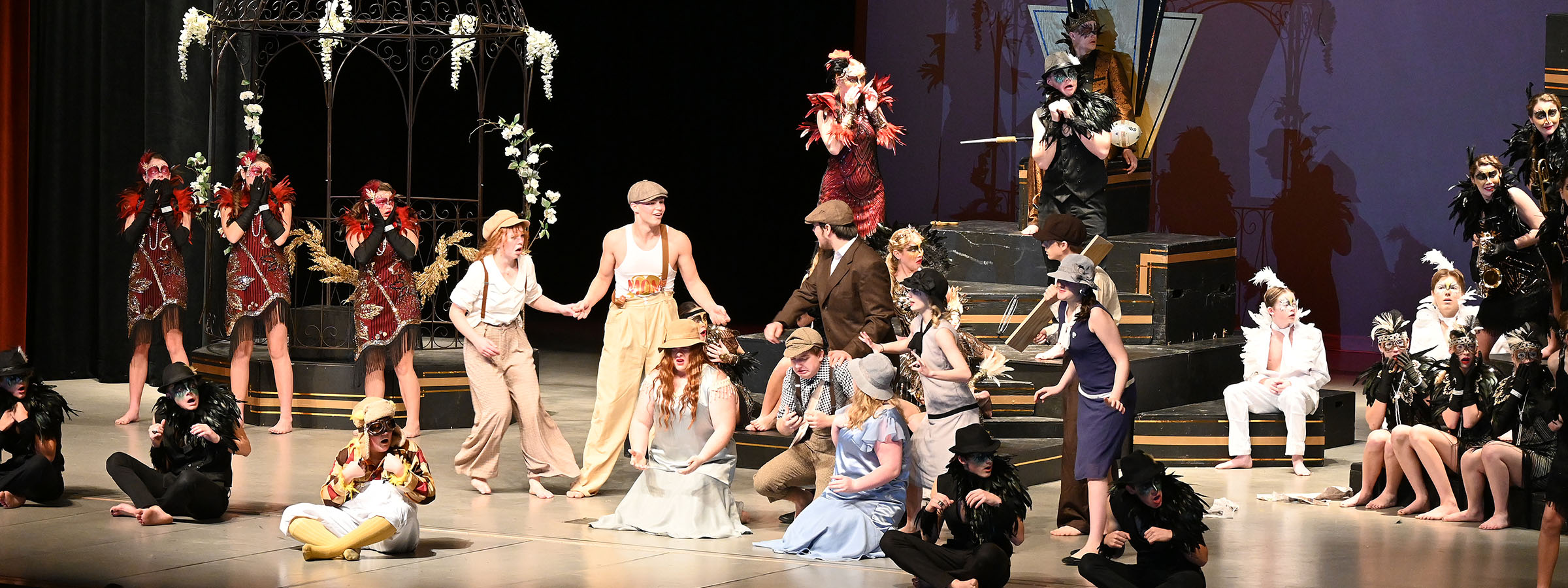 A diverse group of individuals on stage with a man wearing a dress, showcasing inclusivity and acceptance.