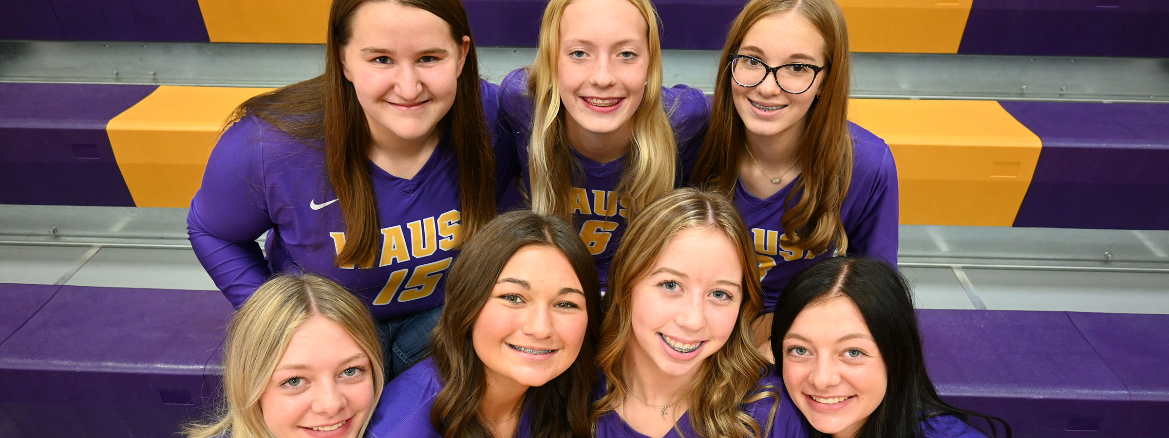 Group of female volleyball players smiling for team photo.