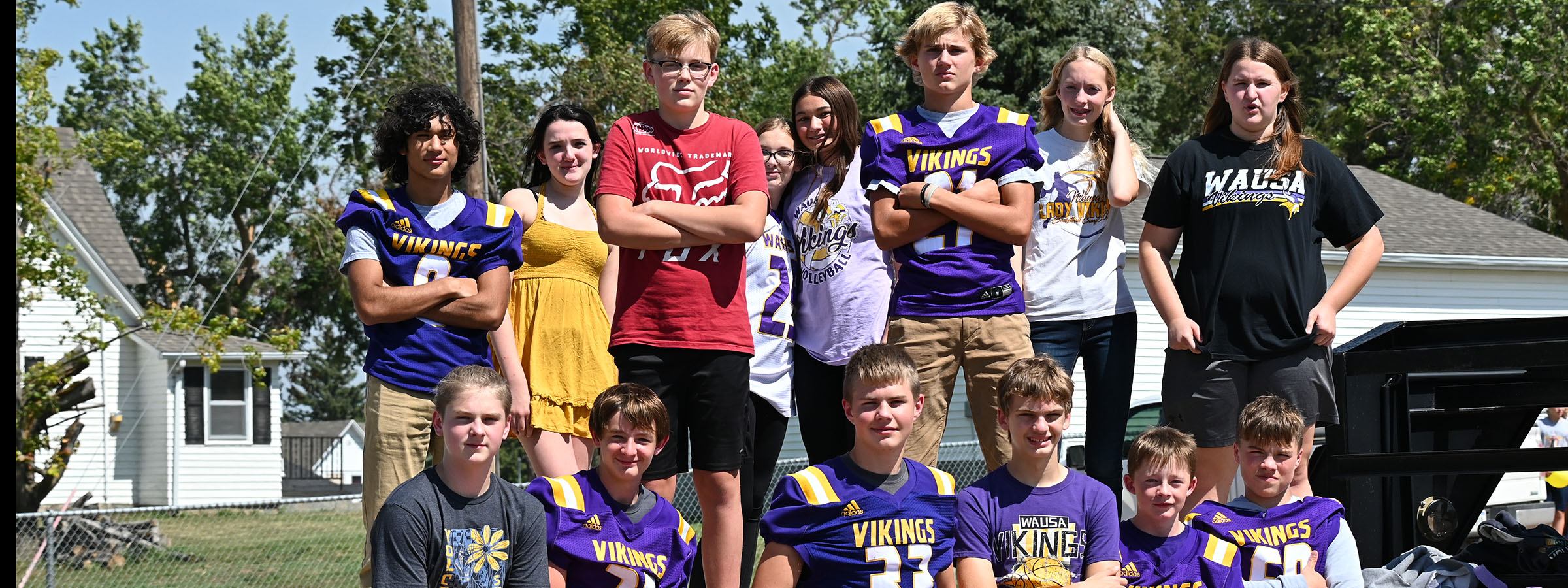 A group of young people in purple and gold uniforms, standing together with smiles, ready for a team photo.