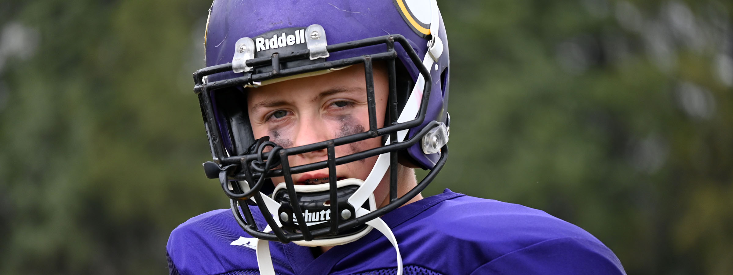 A young man in a purple helmet and uniform.