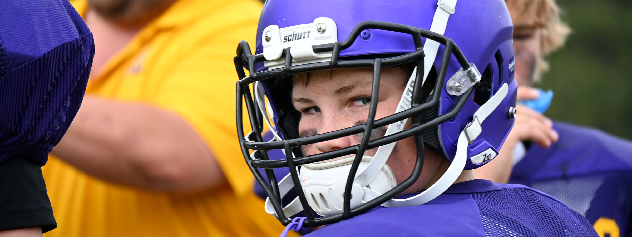 A young boy in a helmet and purple jersey, ready for sports practice.