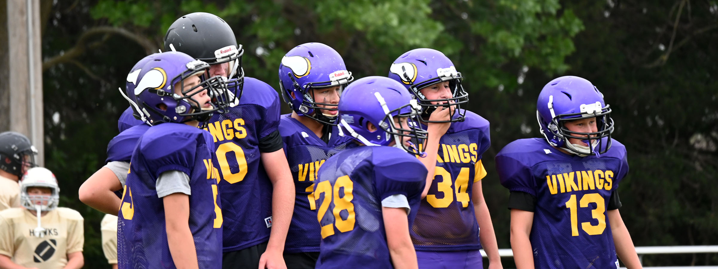 A row of young football players in uniform, standing side by side on the field.