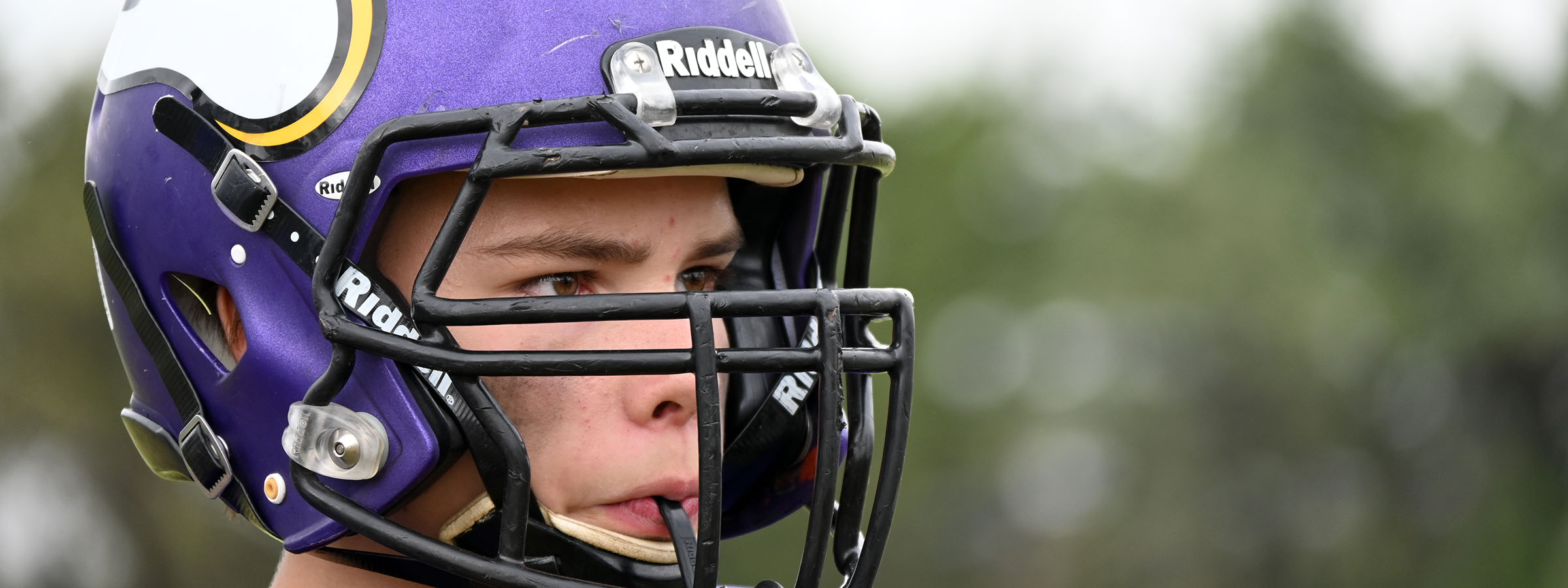 A young man in a helmet and purple jersey, ready for a game of football.