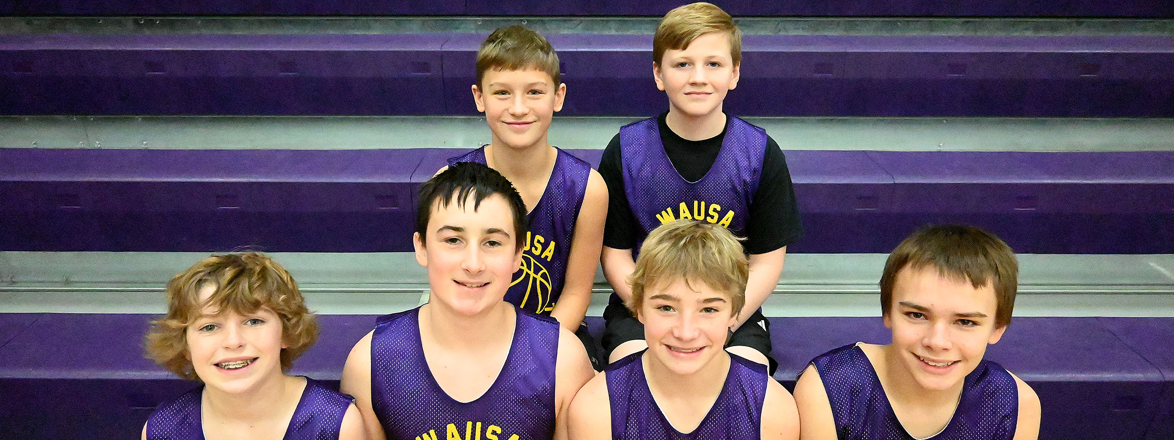 A group of young boys in purple basketball uniforms playing on the court.