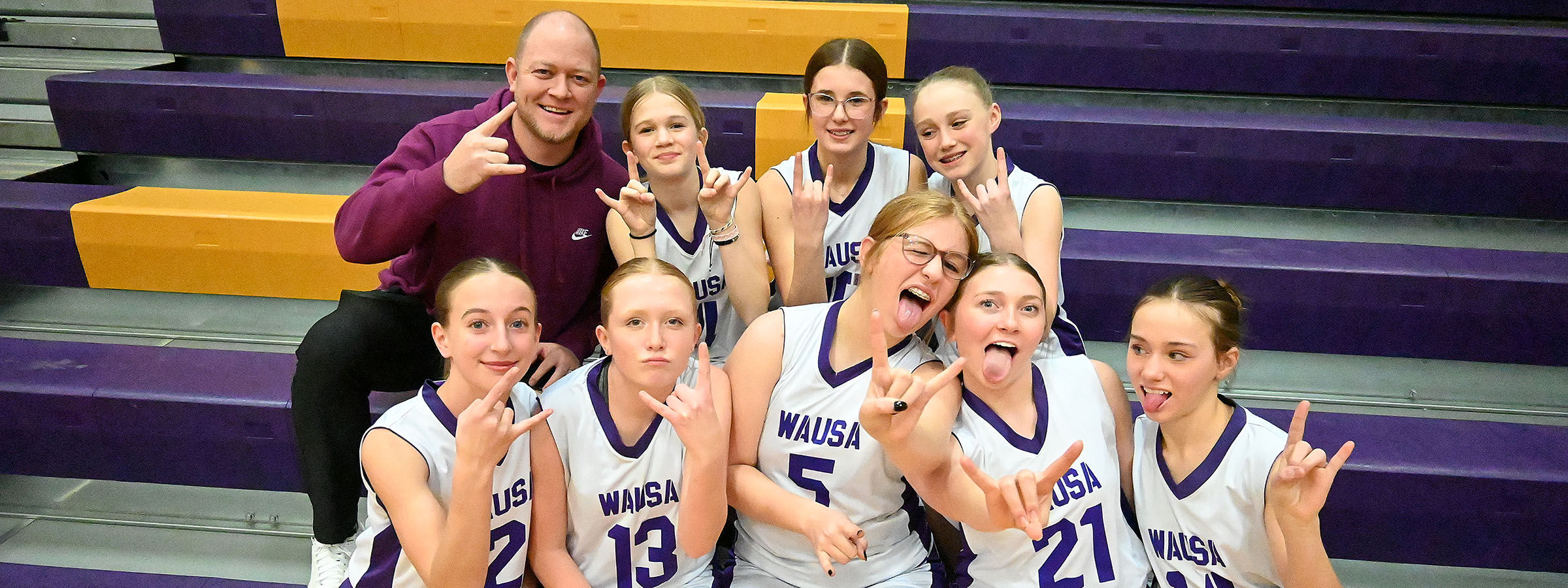 The girls basketball team stands together, smiling for a group photo, showcasing their unity and team spirit.