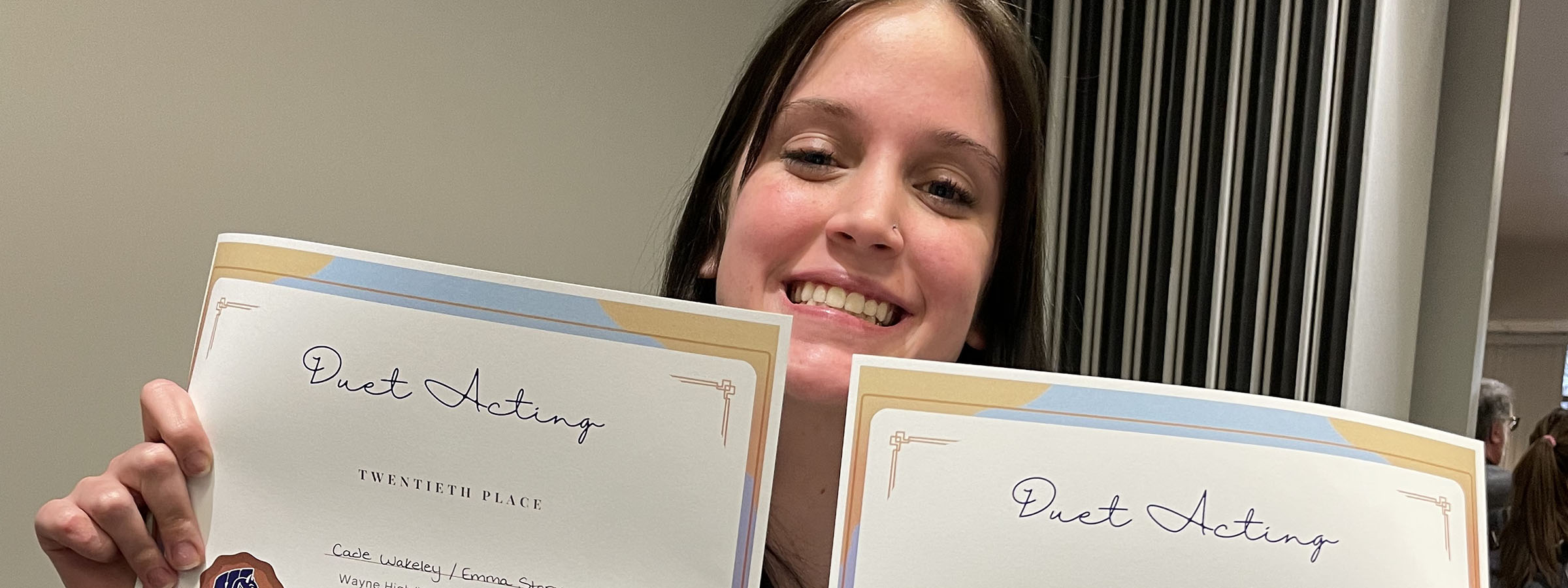 A woman proudly displaying two certificates in front of her.