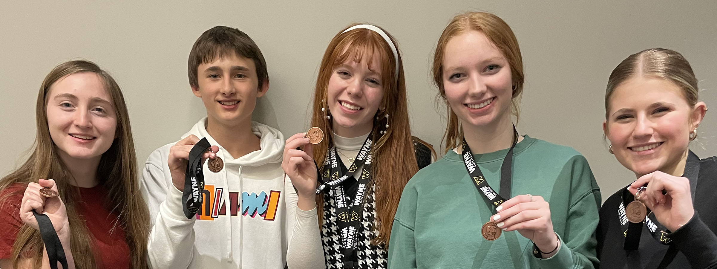 Five young individuals proudly display their medals, showcasing their achievements and camaraderie in a celebratory moment.