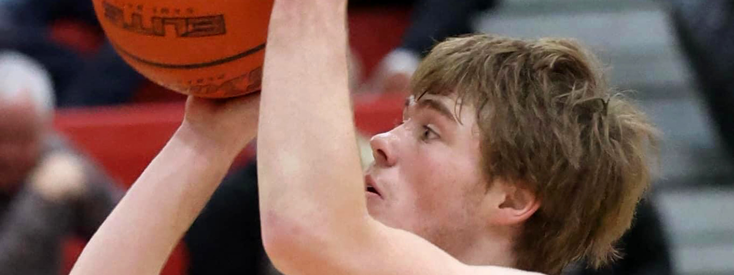 A young man prepares to shoot a basketball, poised and focused on the hoop ahead of him.