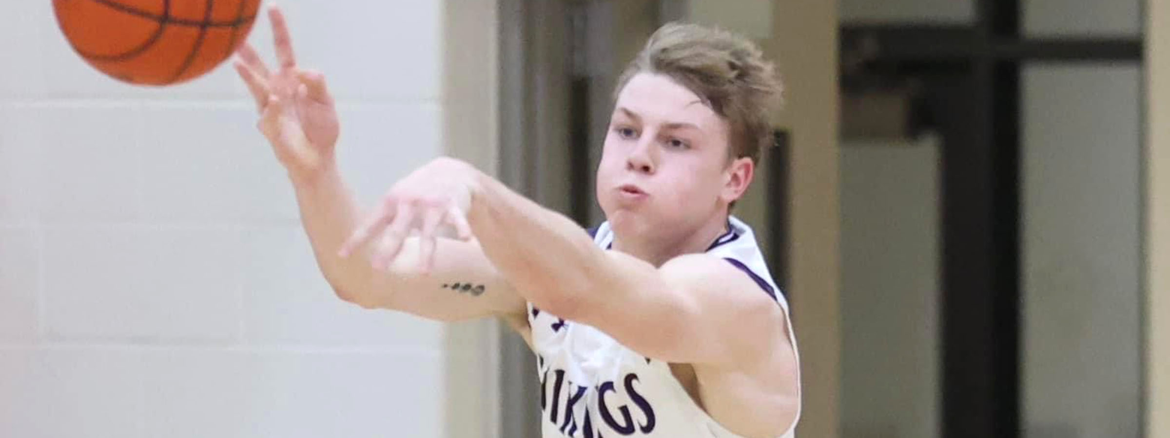 A young man in a basketball court, ready to shoot a basketball into the hoop.