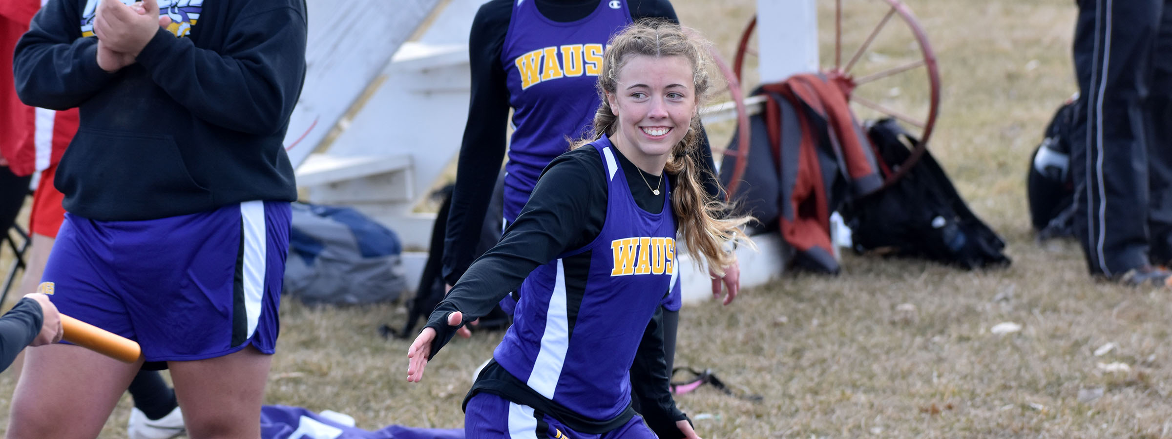 A girl in purple and black uniform holding a bat.