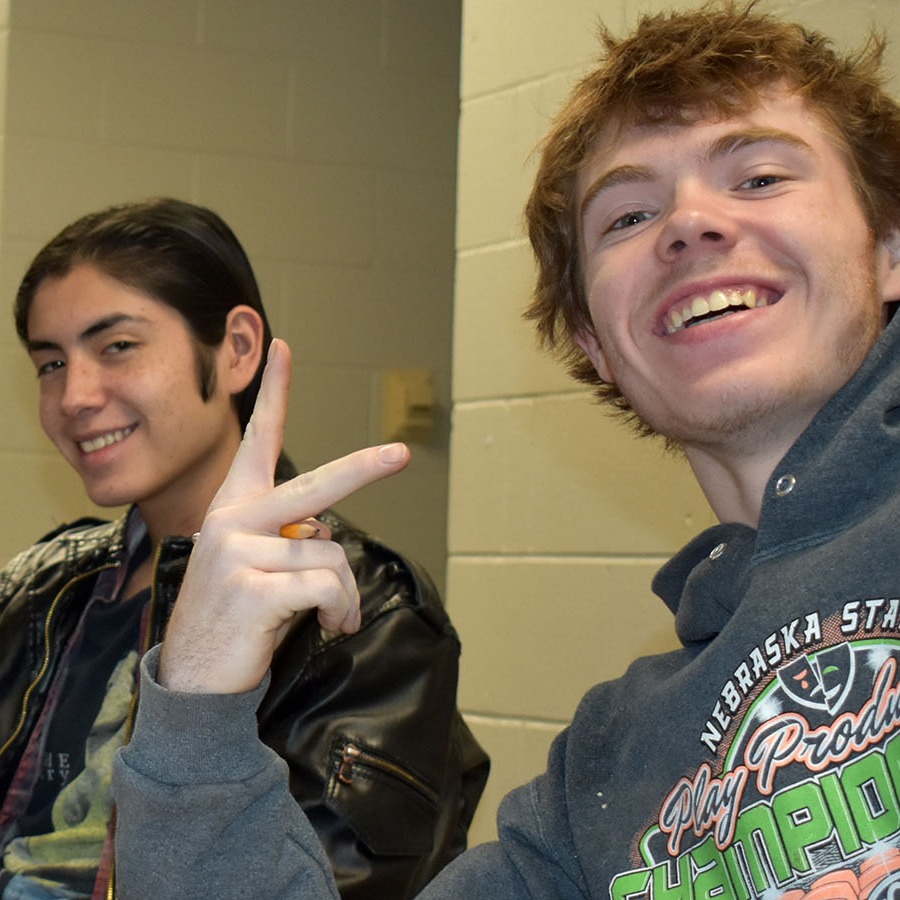 Two boys sitting at a table, focused on a laptop screen.