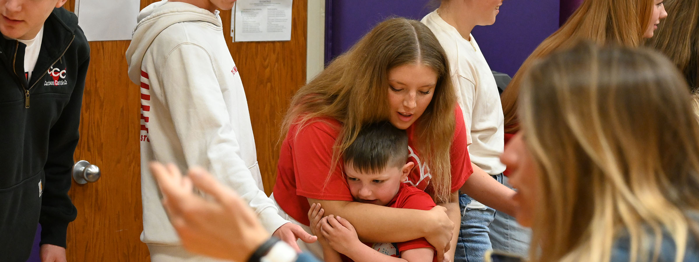  woman embraces a child in a gymnasium.