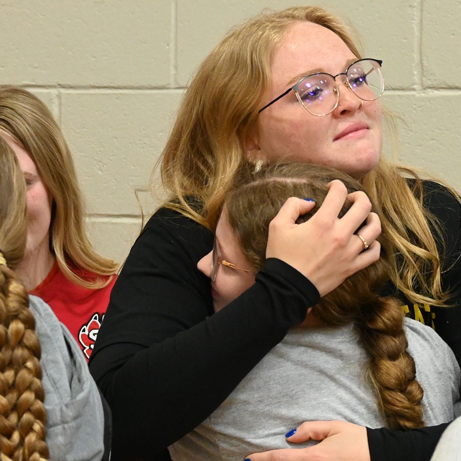 A woman embraces a young girl in a crowd of people.