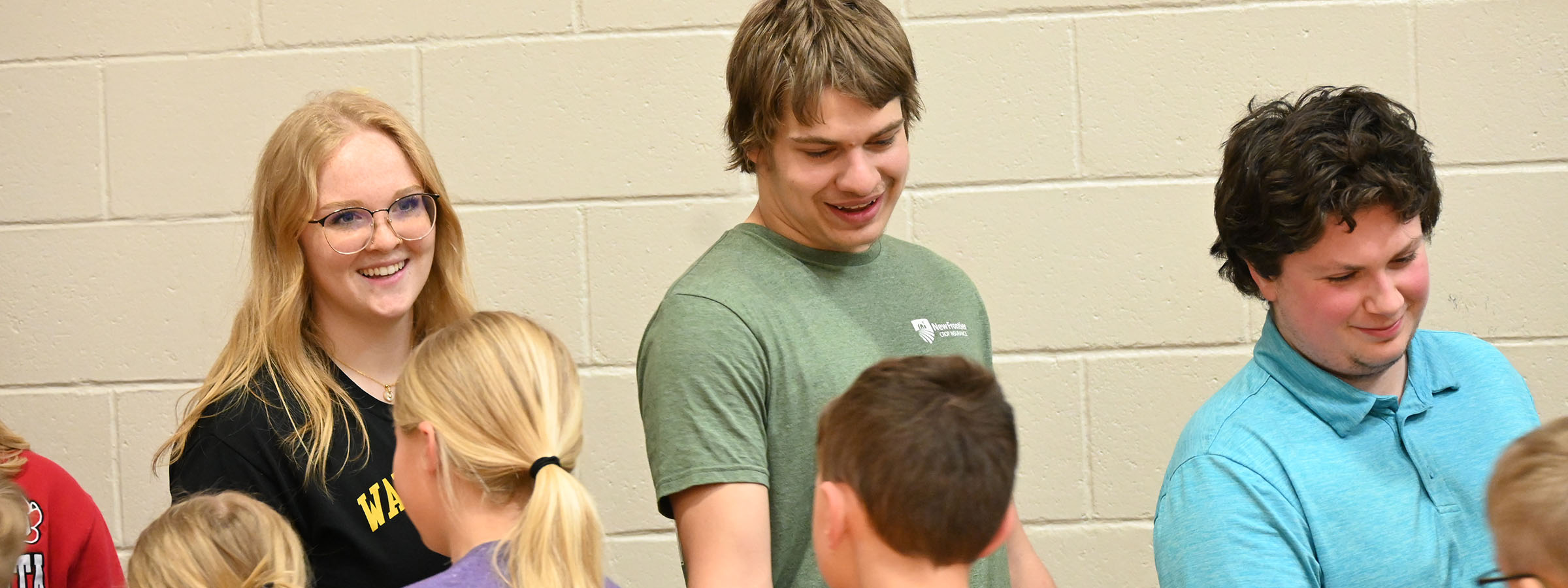 A group of young people standing around a table, engaged in conversation and socializing.