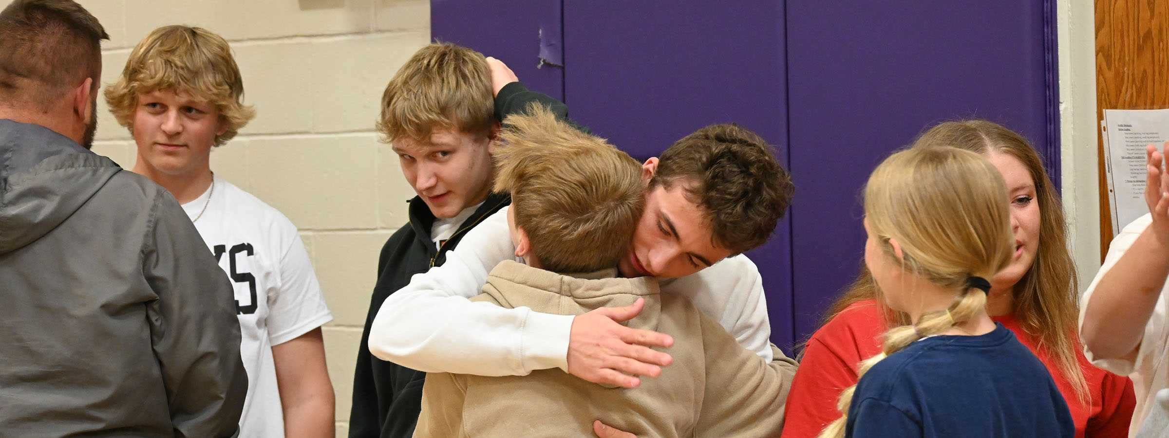 A diverse group of individuals embracing each other warmly in a gym setting.