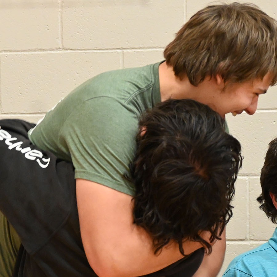 A diverse group of individuals embracing each other warmly in a gym setting, showcasing camaraderie and support.