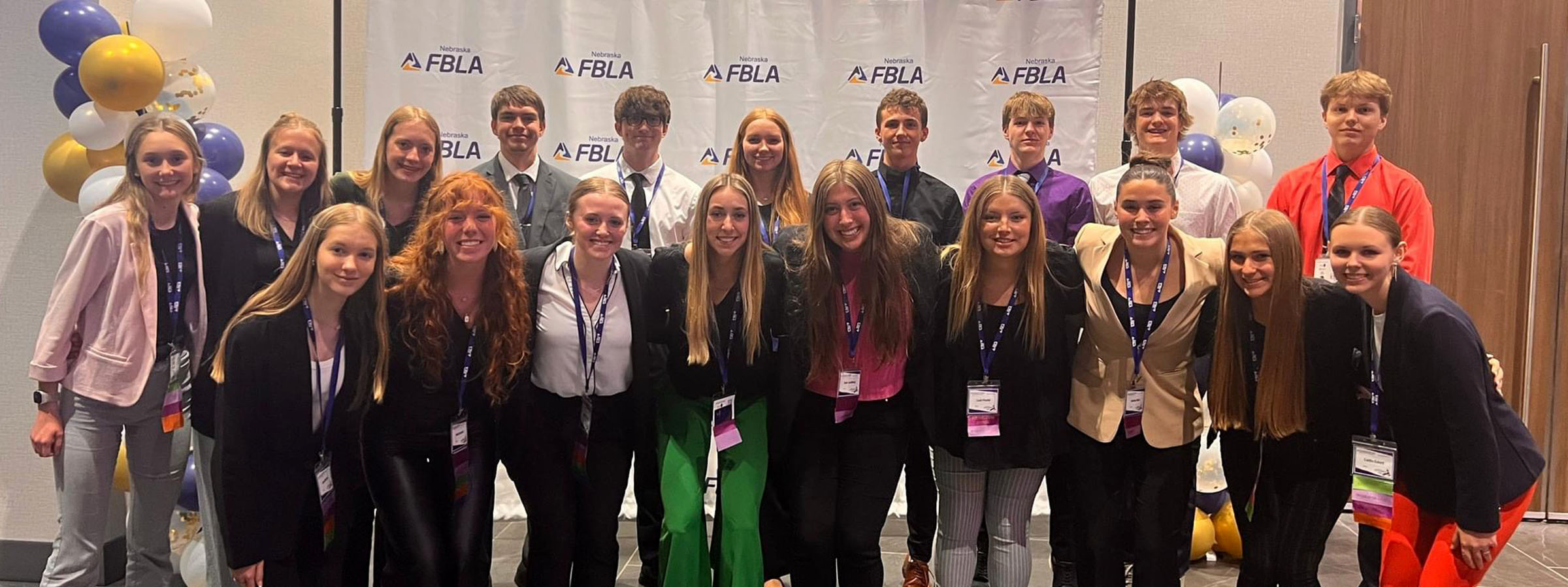 A diverse group of young people standing in front of a banner at an event.