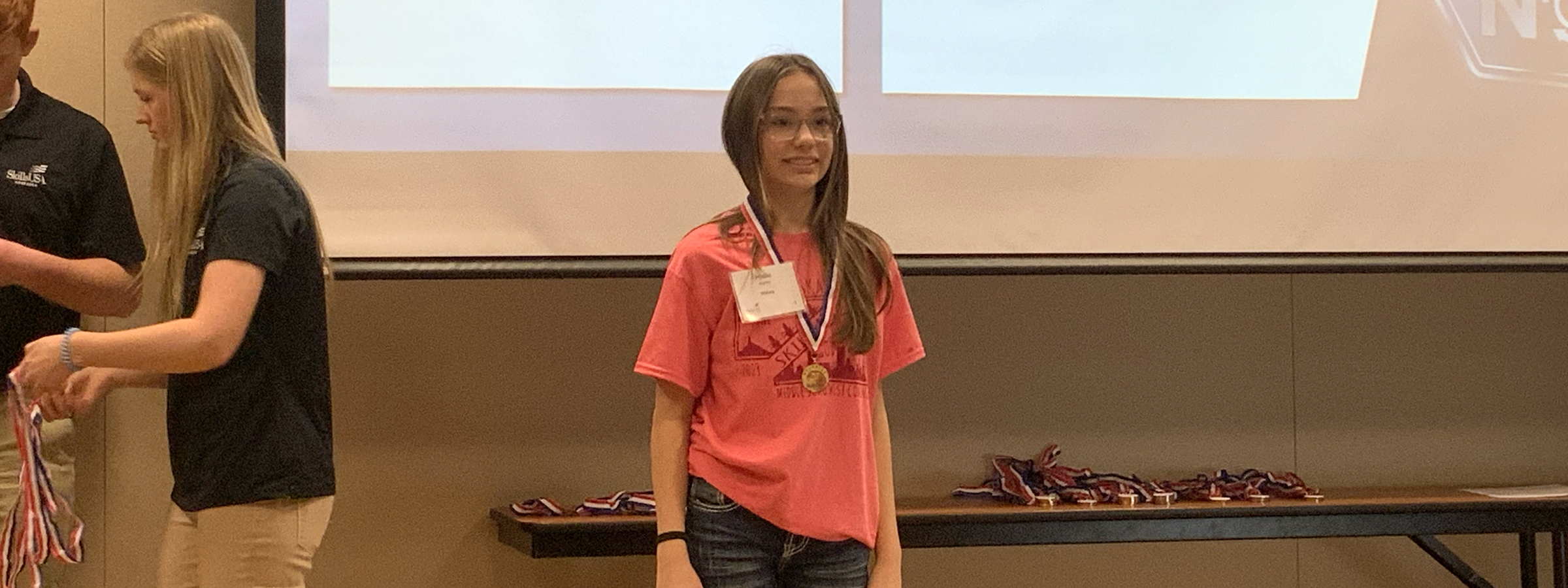  A girl in a pink shirt standing next to a table.