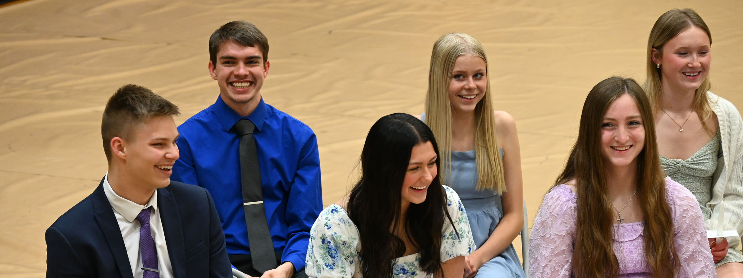 A diverse group of young people sitting cross-legged on the floor, chatting and laughing together.