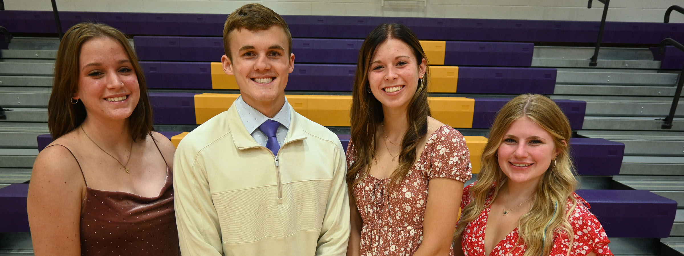 Four young friends posing in a gym, smiling and looking at the camera.