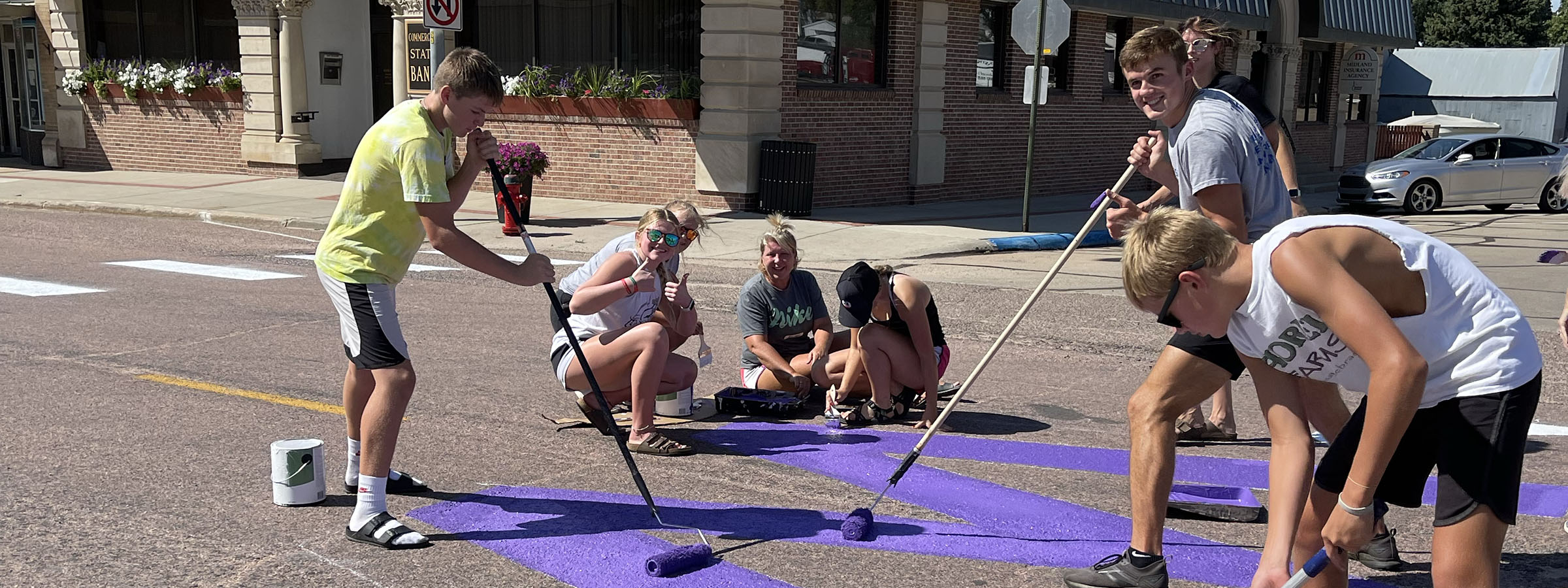 A group of people painting purple on the street during a community art project.