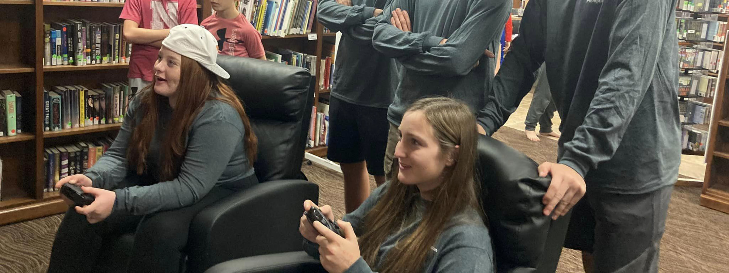 A diverse group of friends enjoying video games together in a cozy library setting, surrounded by books and laughter.