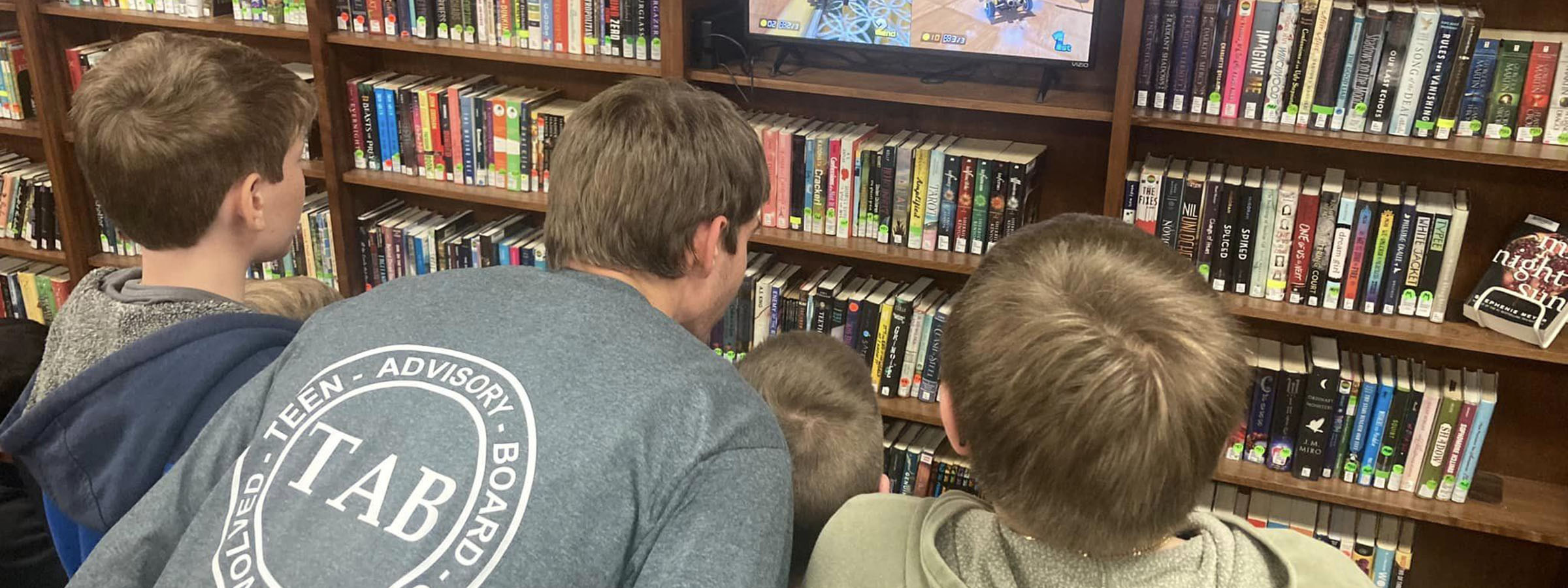 Three boys watching TV in library.