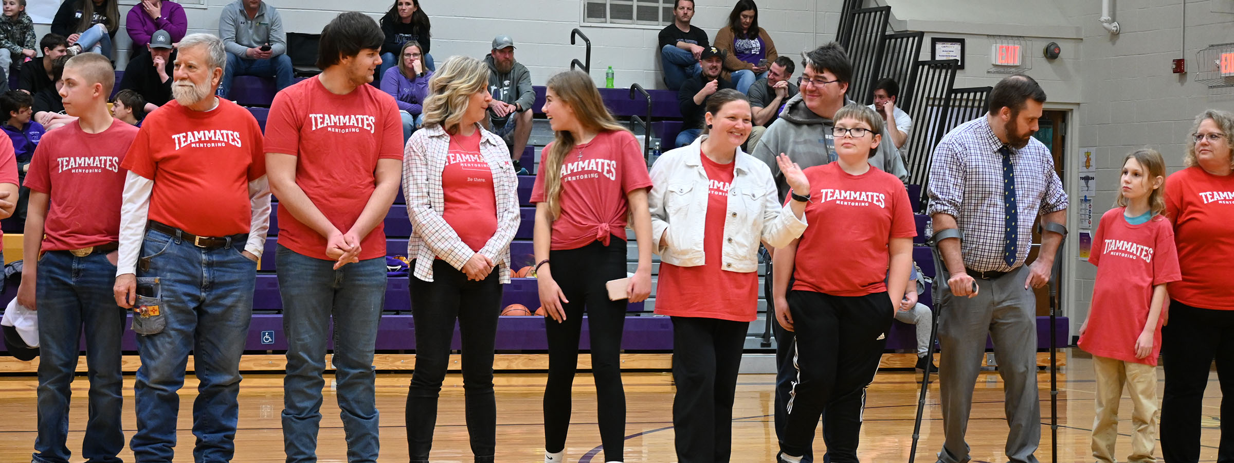  A diverse group of people standing on a basketball court, ready to play a game together.