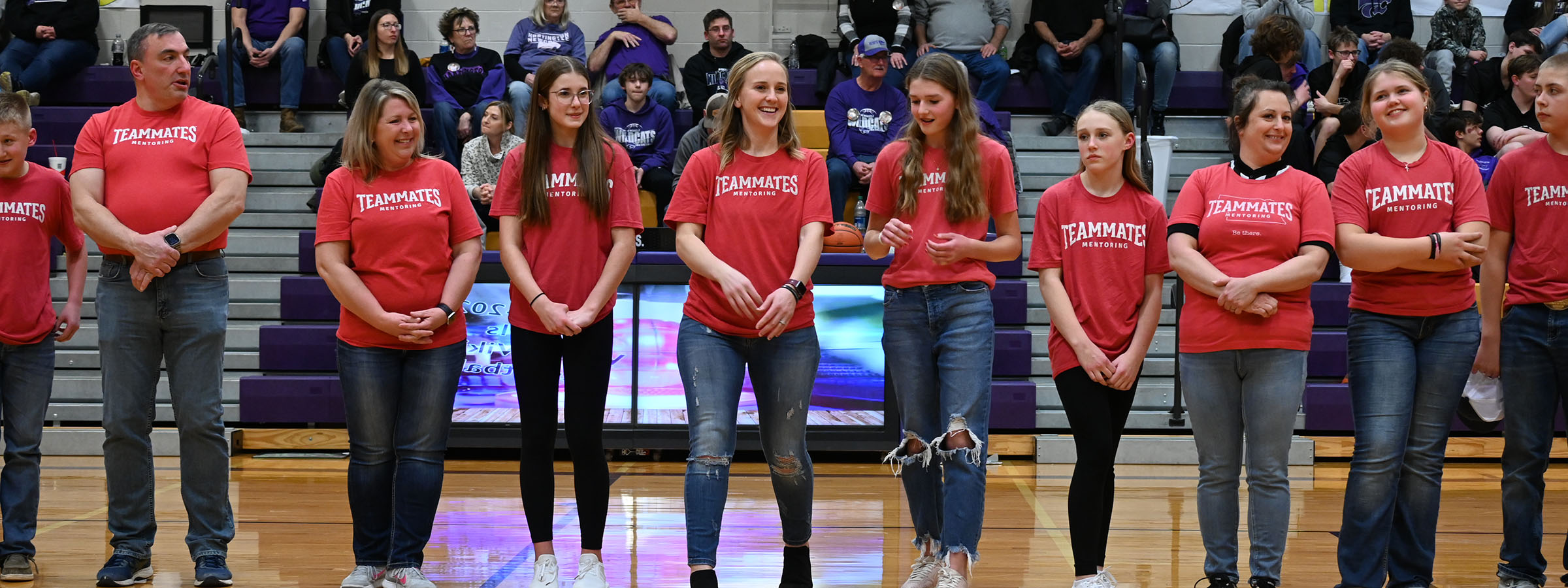  A diverse group of people standing on a basketball court, ready to play a game together.