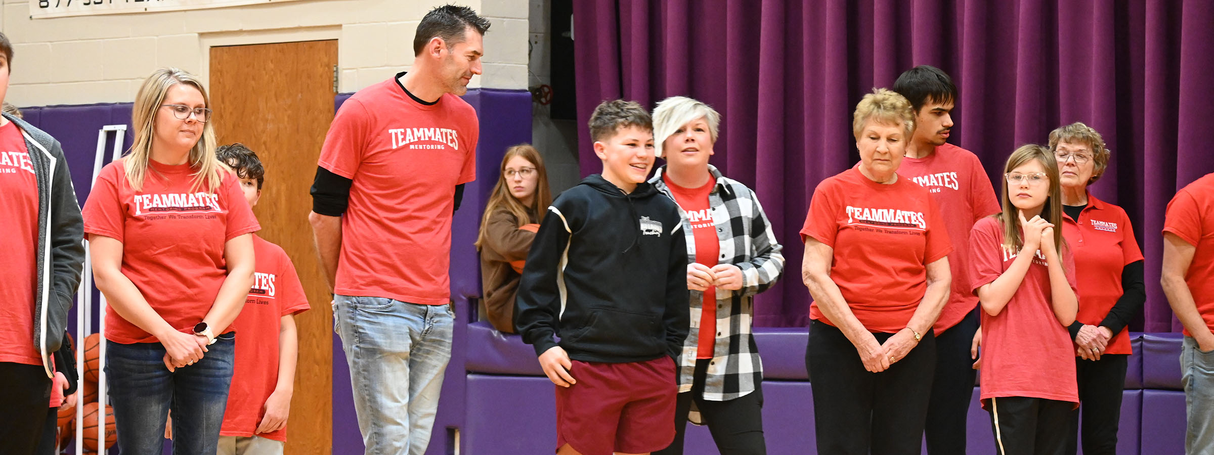 A group of people in red shirts standing in a gym.