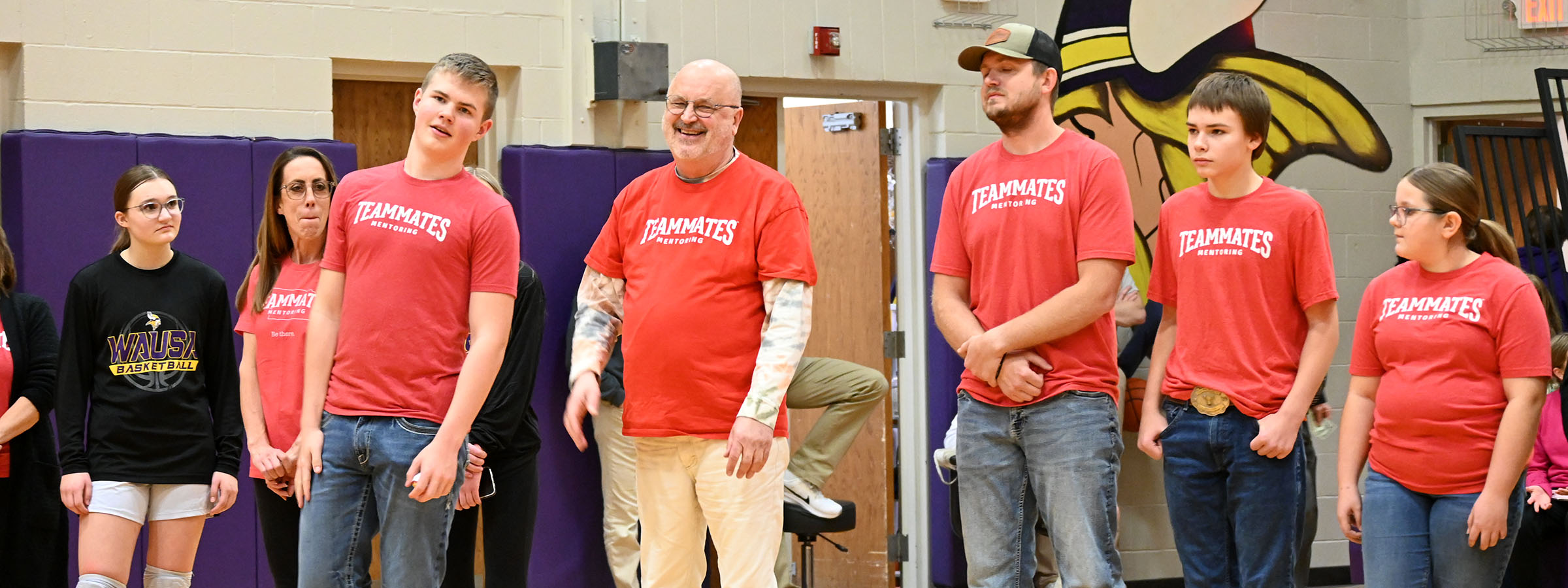 A group of people in red shirts standing in a gym.