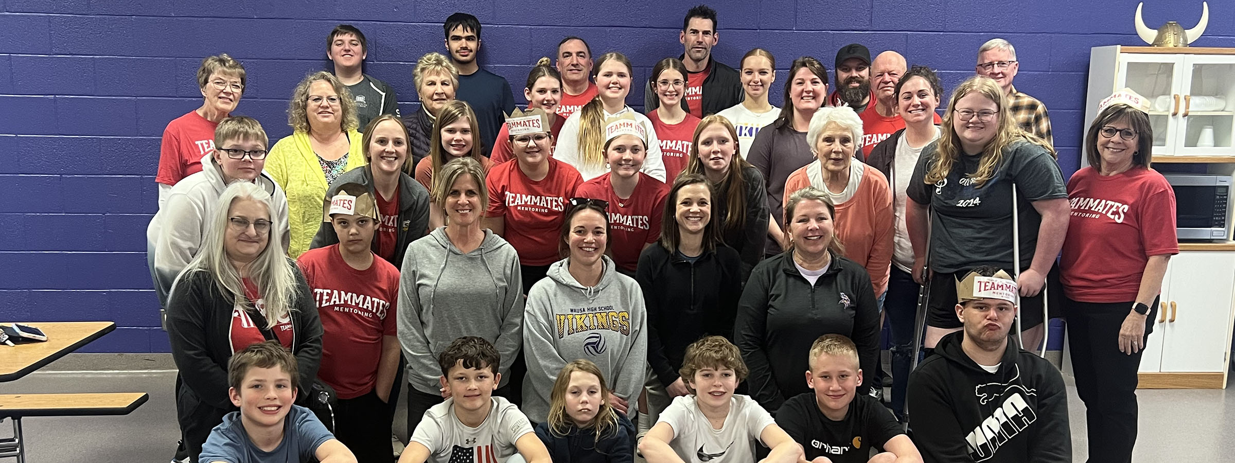 A group of people in red shirts standing in a gym.