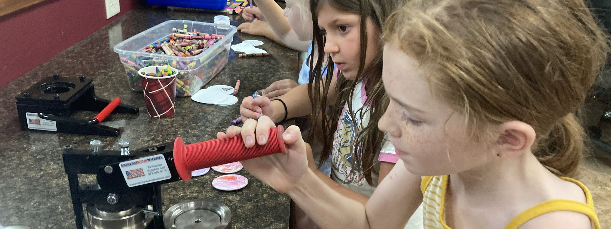 Two girls crafting together at a table with colorful paper and glue.