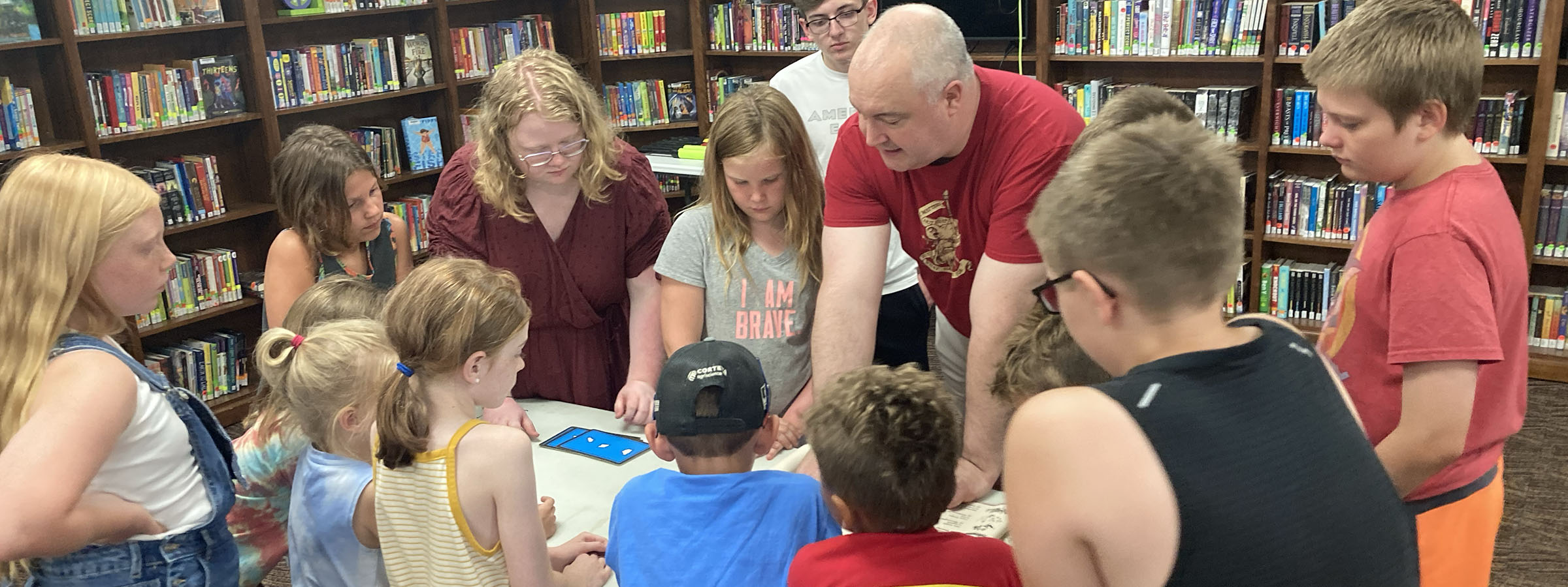 A diverse group of children and adults reading and studying together in a library.