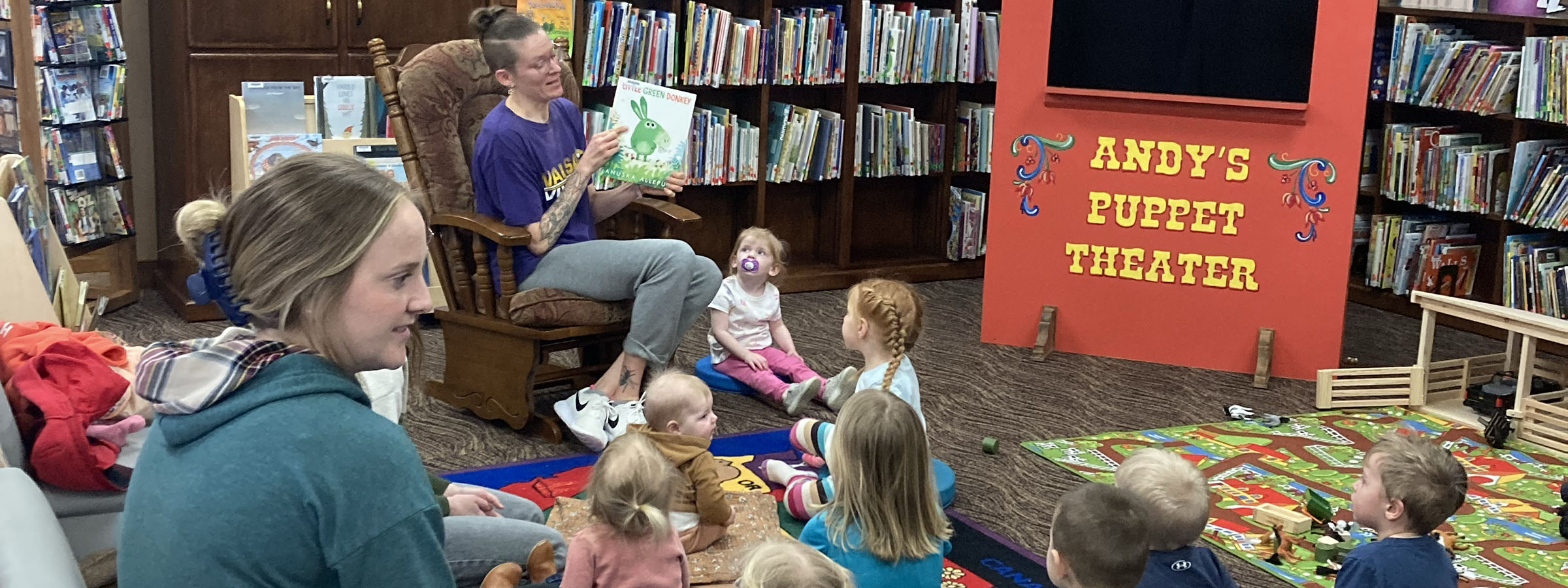 A group of children gathered in a cozy library, happily reading stories to one another, surrounded by books.