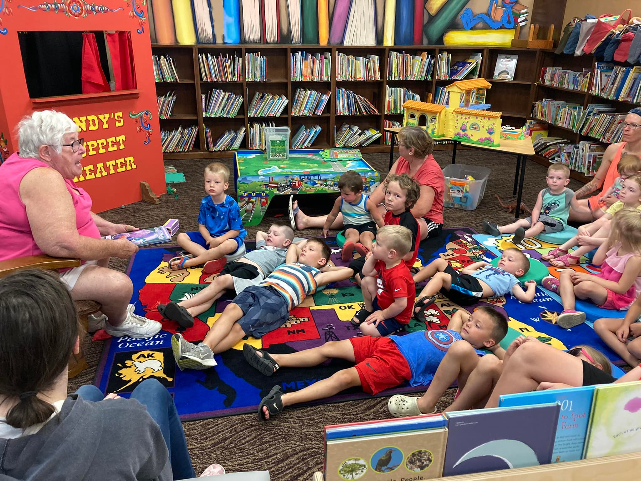 Children sitting on floor, reading books in library.