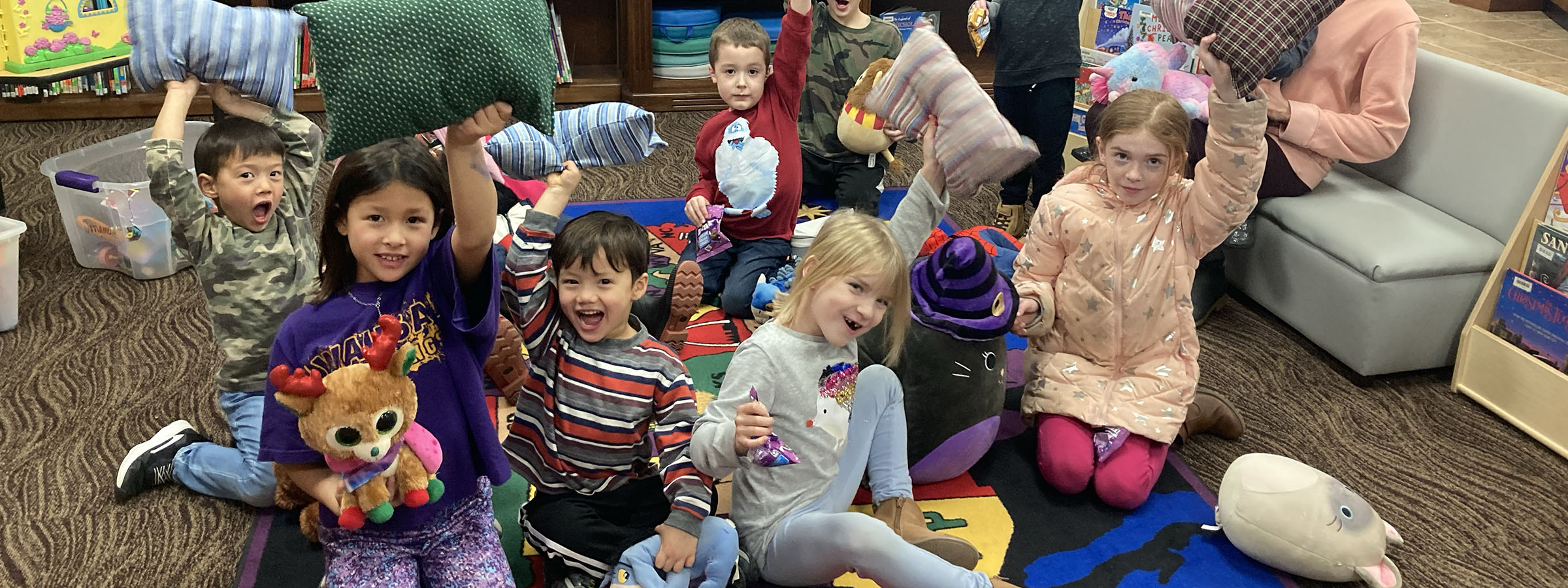 Children sitting on floor, reading books in library.