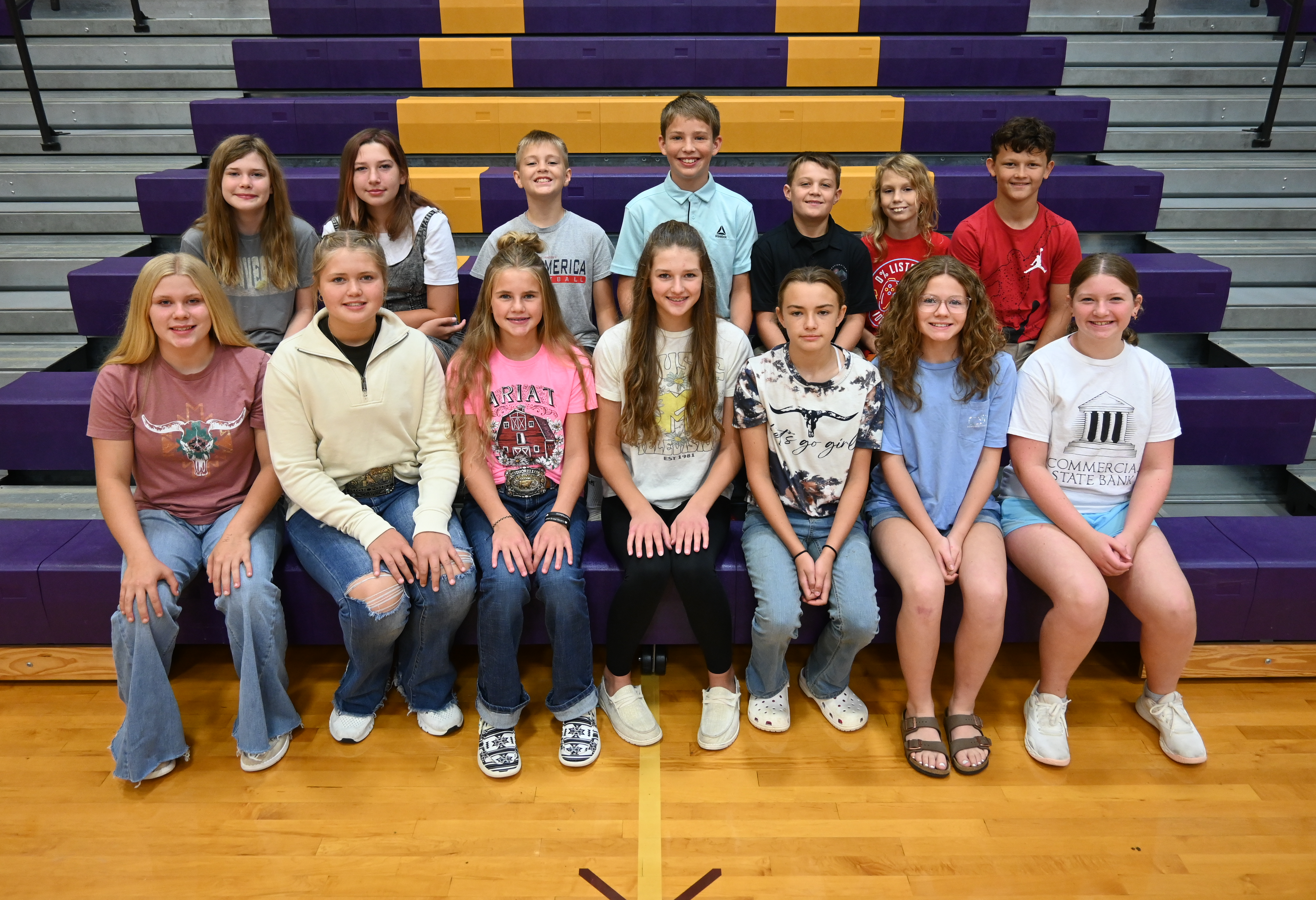 A group of young people sitting on bleachers at a sports event.