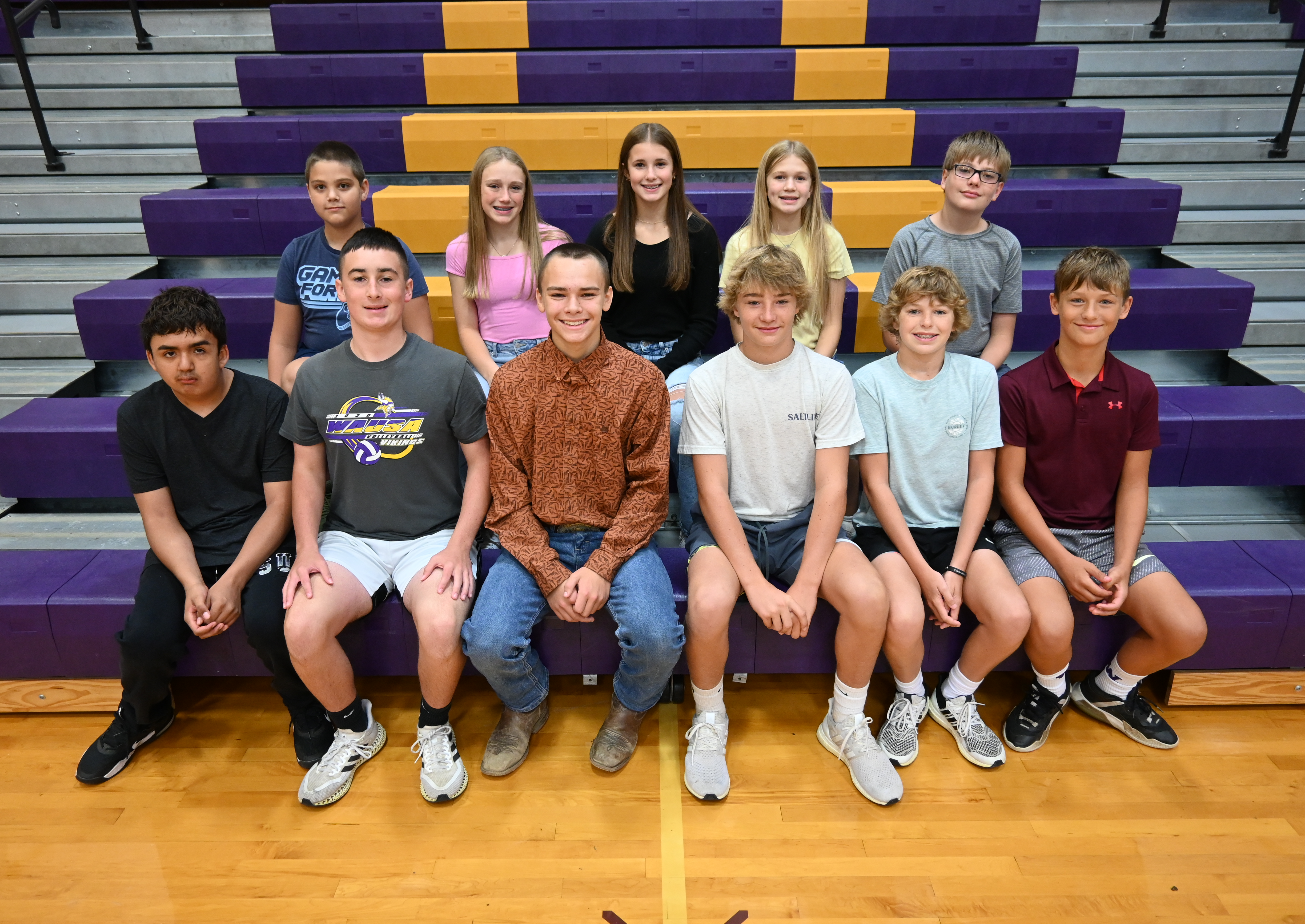 A group of young people sitting on bleachers at a sports event.