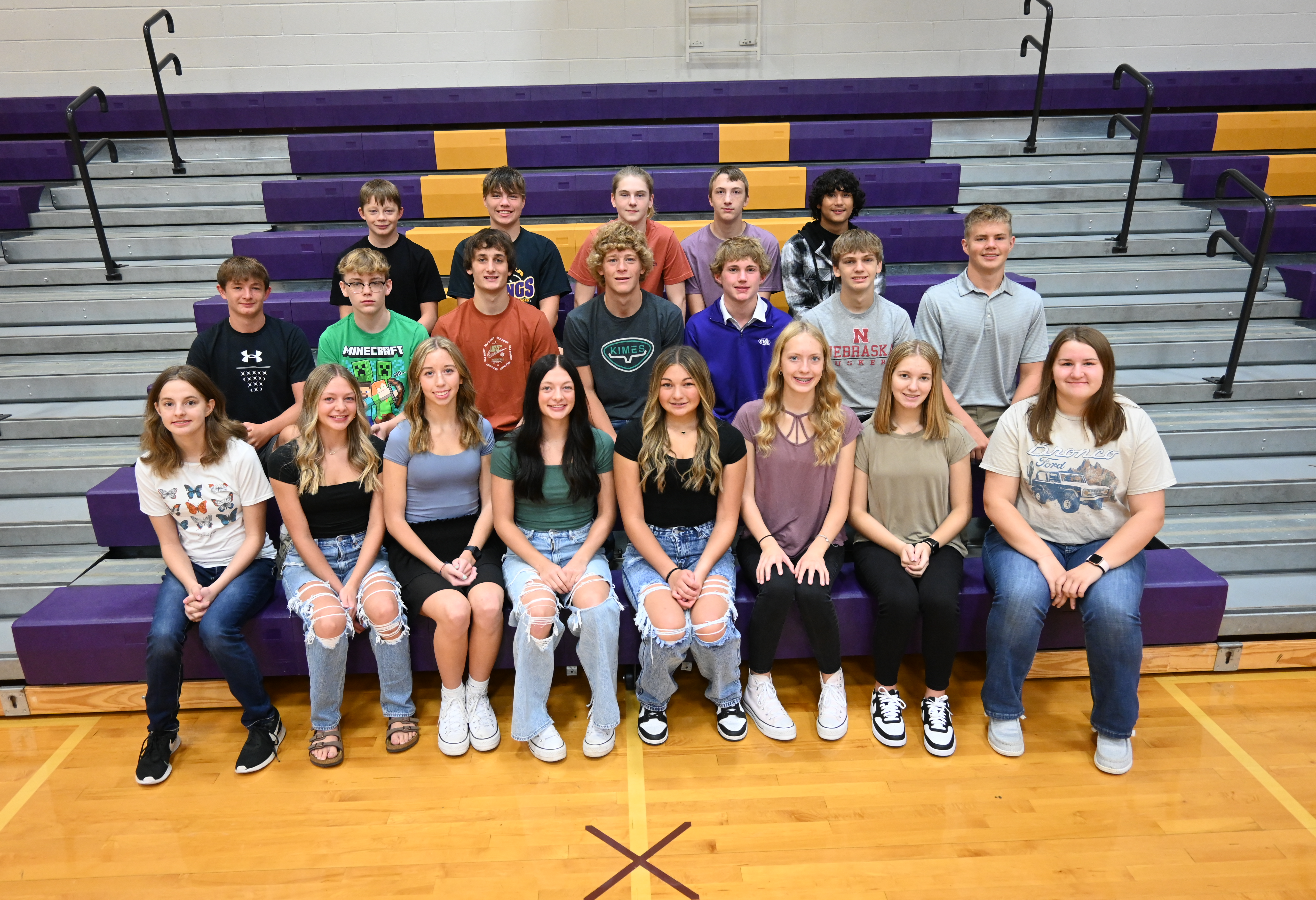 A group of young people sitting on bleachers in a gym.