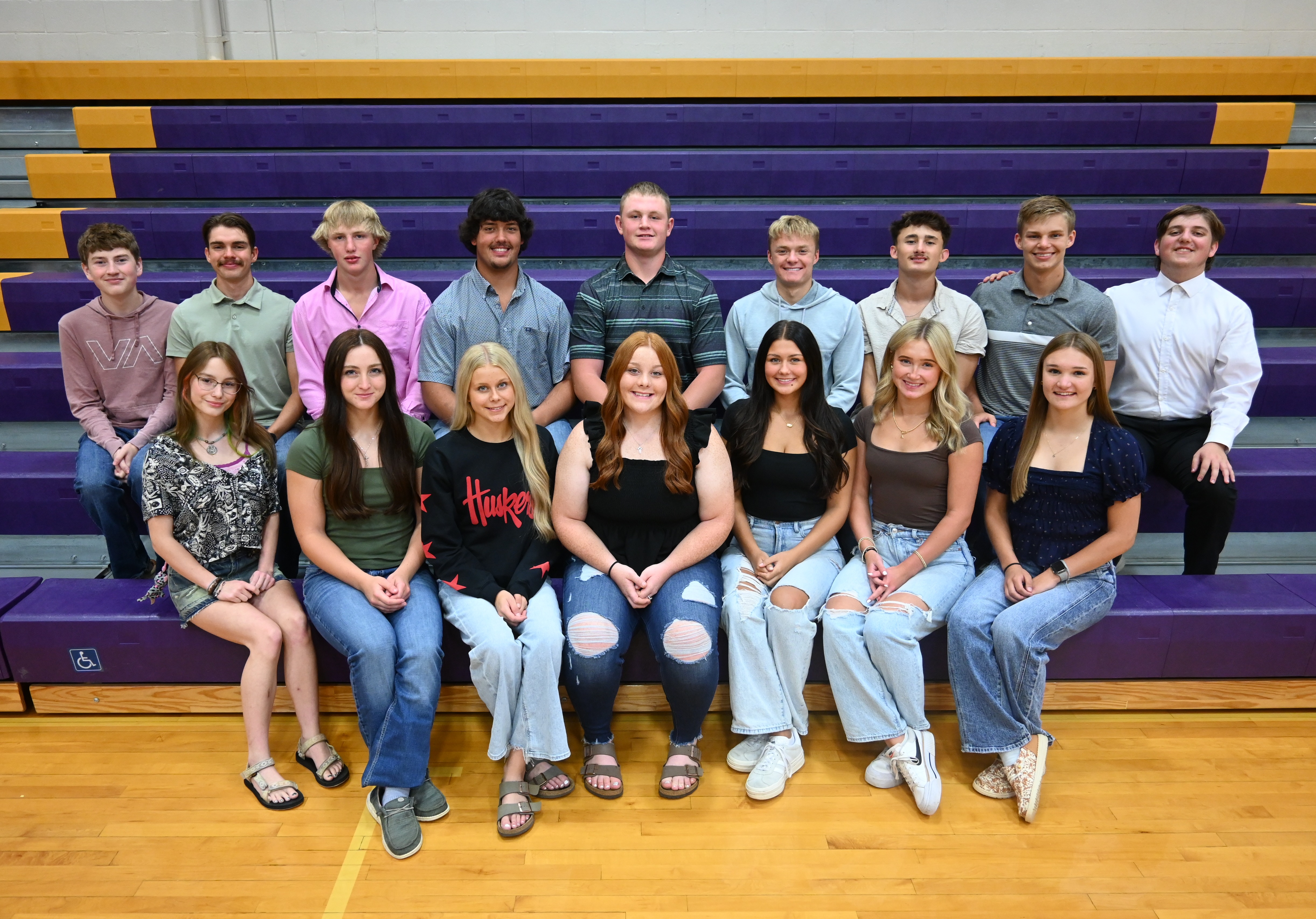 A diverse group of young individuals sitting on bleachers, chatting and laughing together.