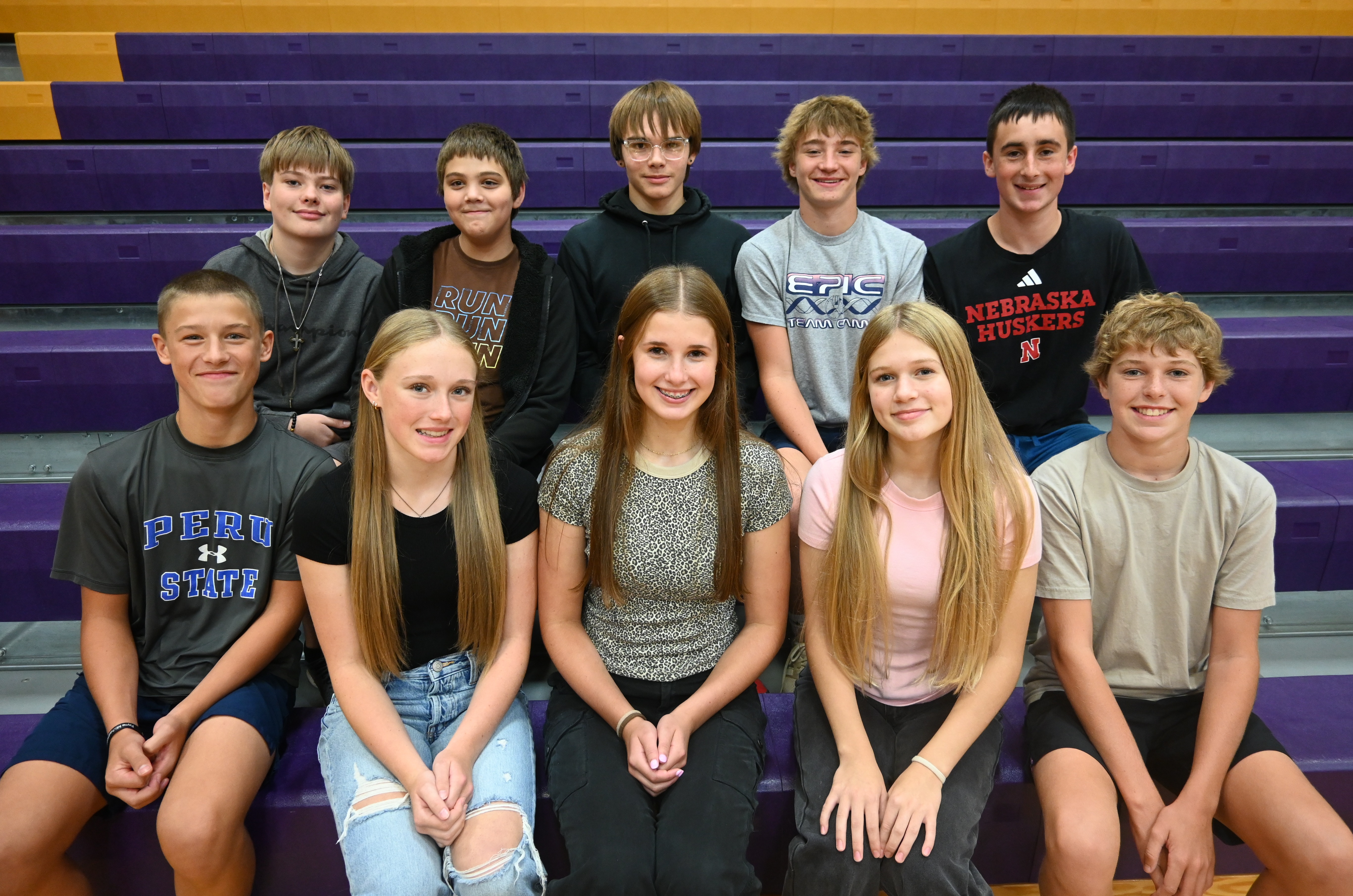 A group of young people sitting on bleachers at a sports event.
