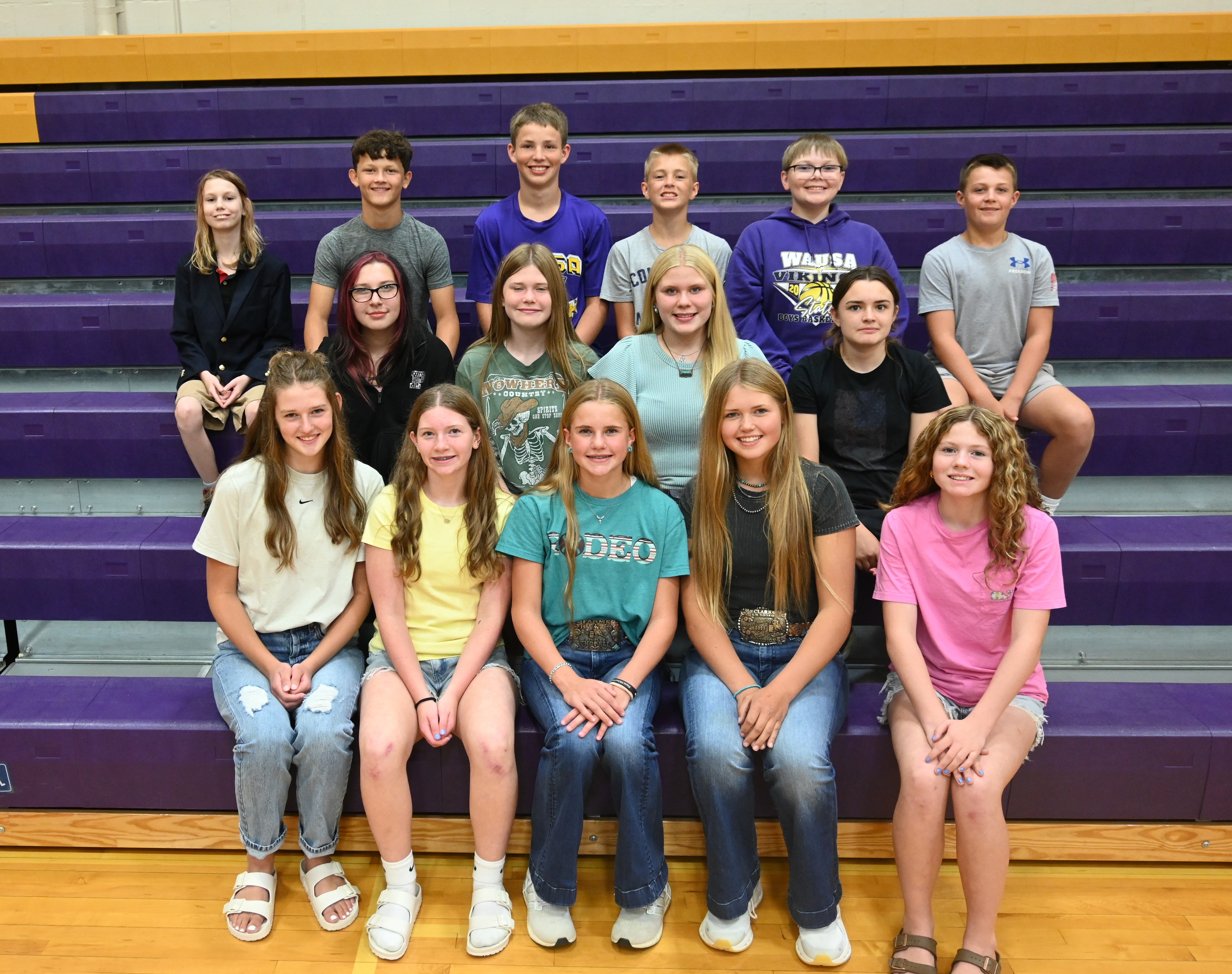 A group of young people sitting on bleachers at a sports event.
