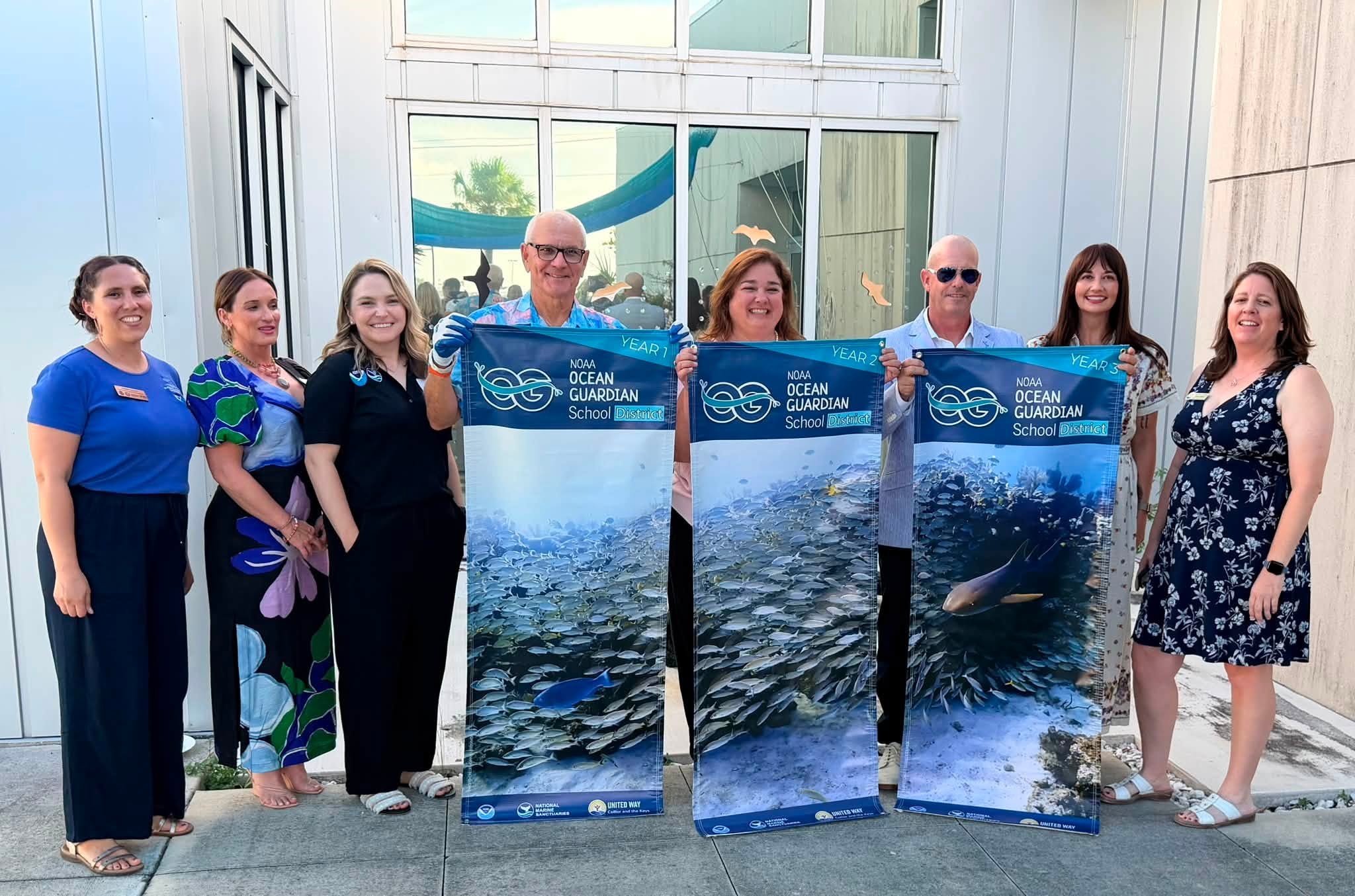 Group of people standing with banners declaring MCSD an Ocean Guardian School District