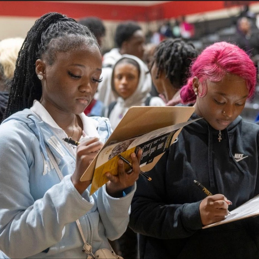 Students in the gym completing college application.