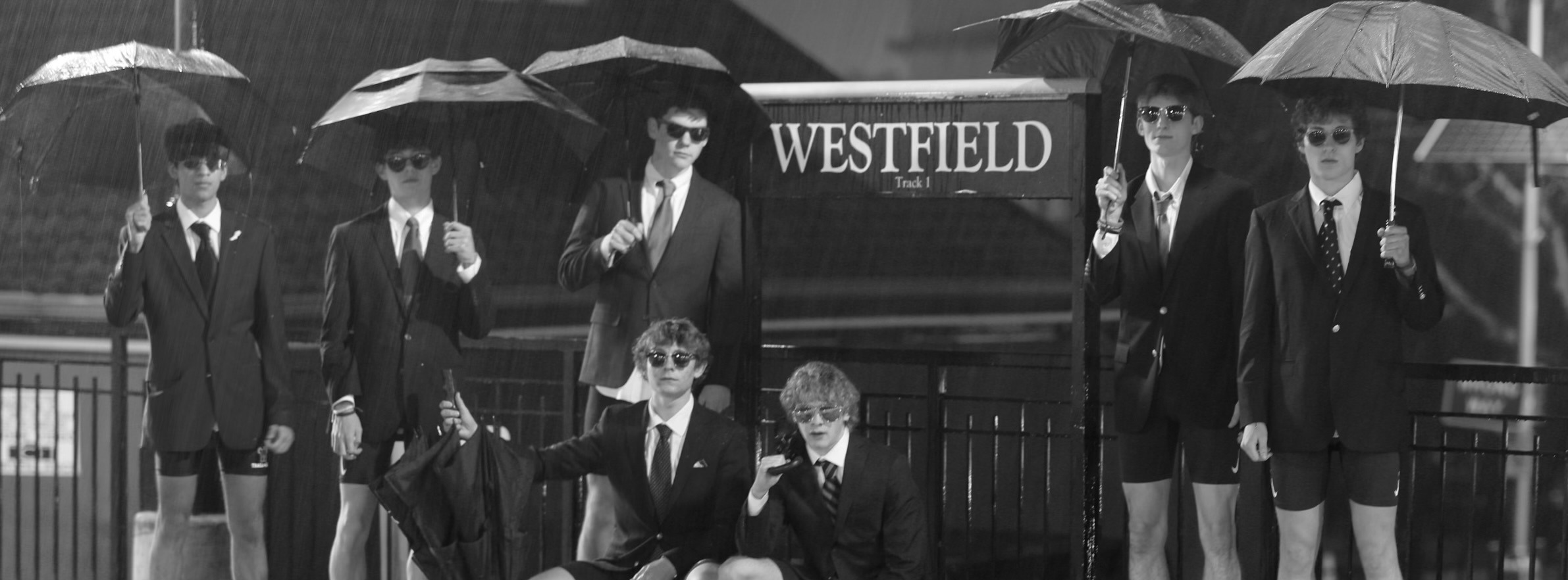 Boys Cross Country Team at Westfield Train Station in the rain with umbrellas