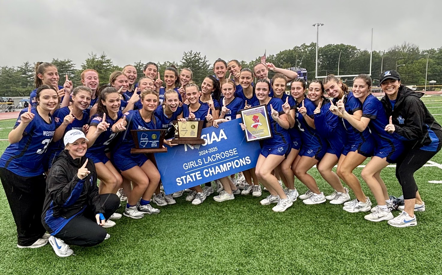 Girls on a turf field holding trophies
