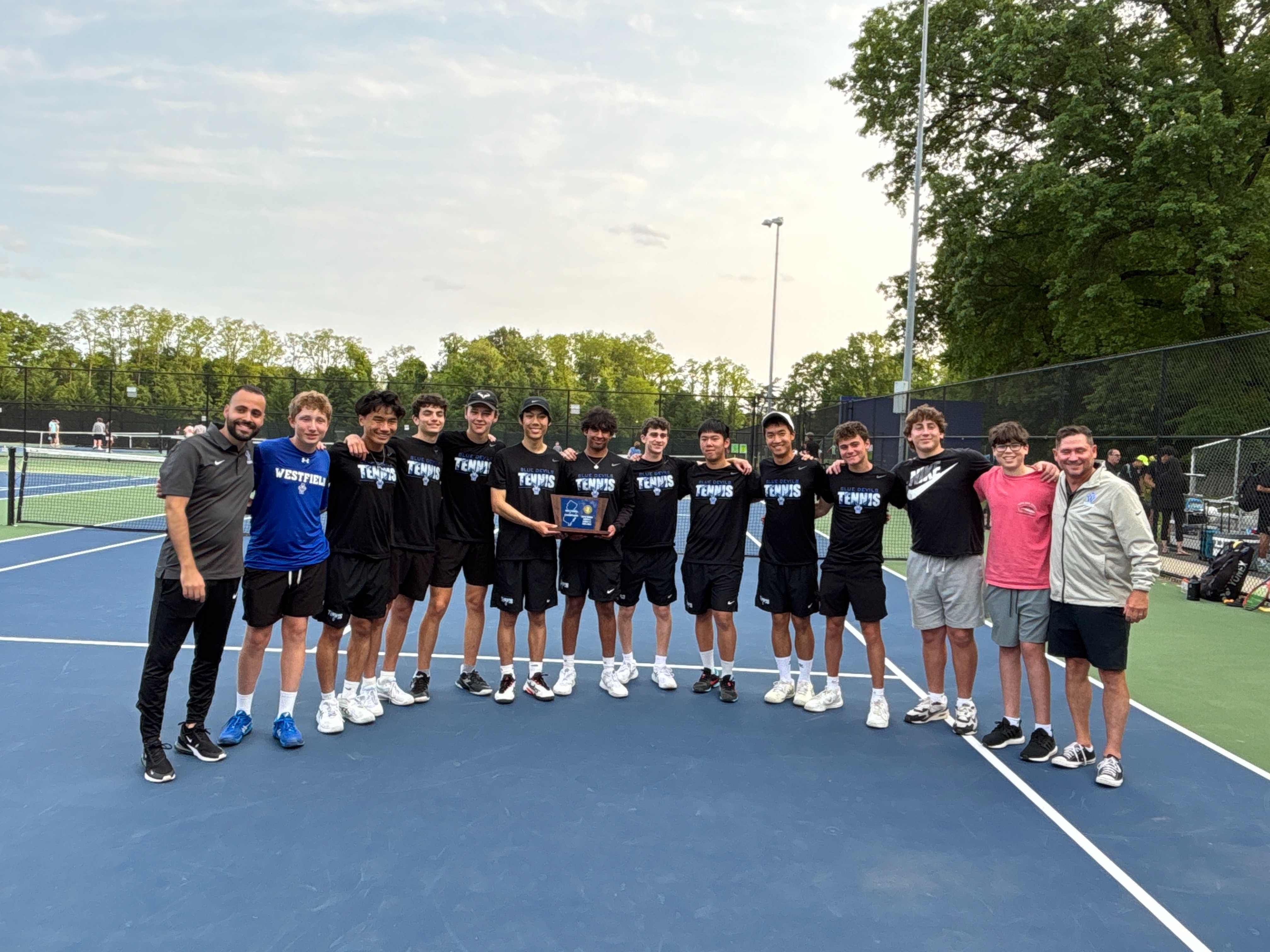 Boys on a tennis court holding a trophy